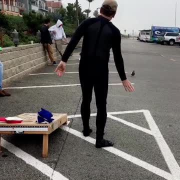 Guy in black outside tossing bean bag