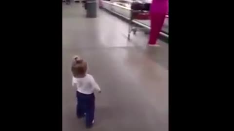 A child wanders in a mall and greets the customers