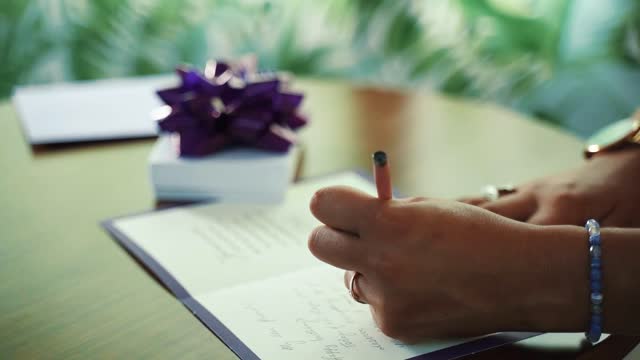 A Person Writing A Message On A Birthday Card