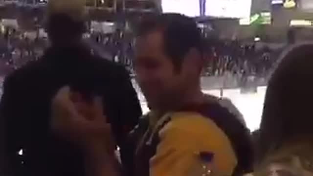 Guy in orange purple sweatshirt throws hockey puck during game