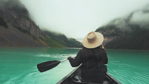 A Woman Paddling A Boat In Lake Louise