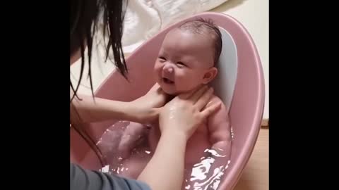 cute baby laughs non-stop while being bathed and massaged by his mother