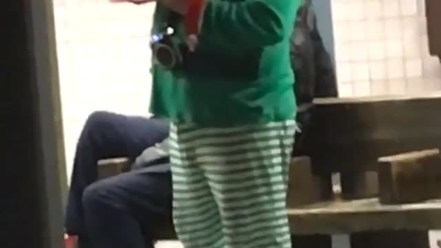 Man in elf costume sings another man with long hair air guitars