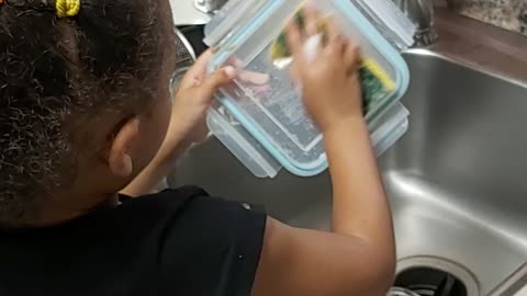 Baby girl is washing dishes