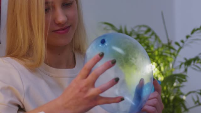 A beautiful teenager holding an airfilled condom.