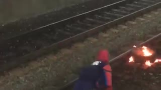 Guy on train subway tracks spiderman costume fire grill security tackle