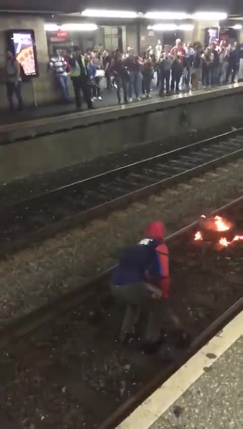 Guy on train subway tracks spiderman costume fire grill security tackle