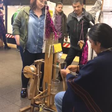 Crowed standing around woman weaving bracelets subway