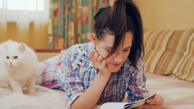 Young girl read the notes in notebook, preparing to exam; white cat near girl
