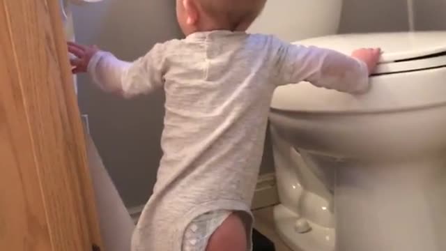 Baby pulling out roll of toilet paper, loses balance and face hits toilet