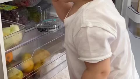 Cute boy eating directly for fridge