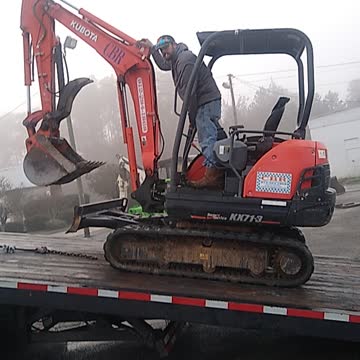 Loading a small excavator on the back of a rollback
