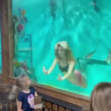 Little girl sees mermaid in the aquarium and gets scared.