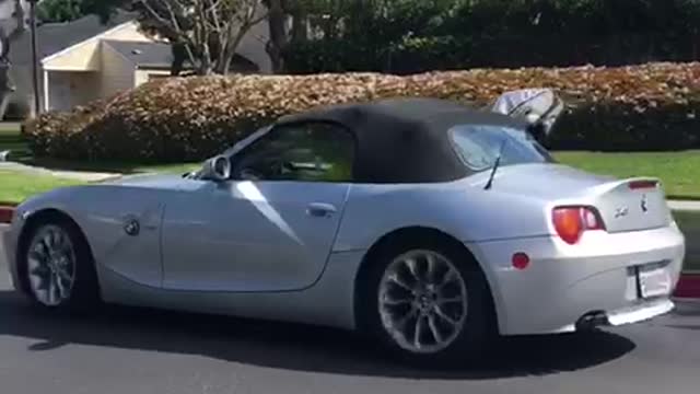 Guy bmw z4 coupe convertible driving with surfboard out of window