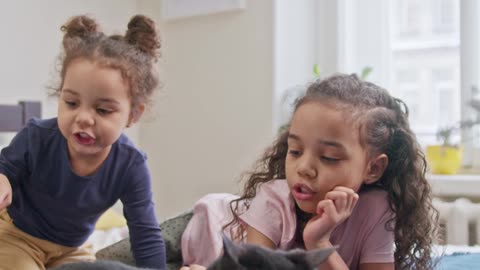 Kids Petting Their Cat On The Bed