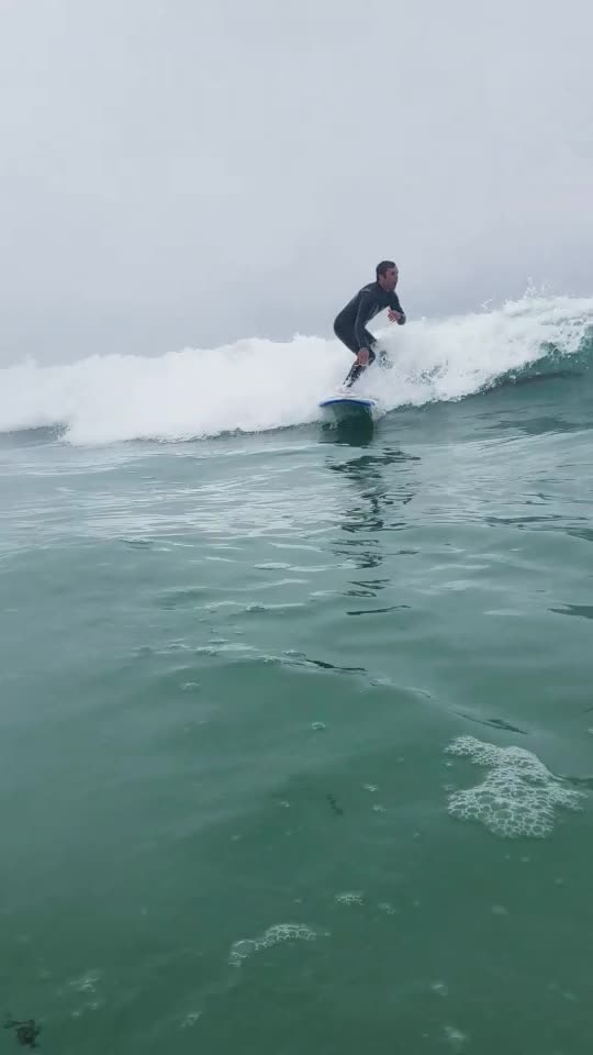 Guy in blue wet suite surfing high fives guy filming