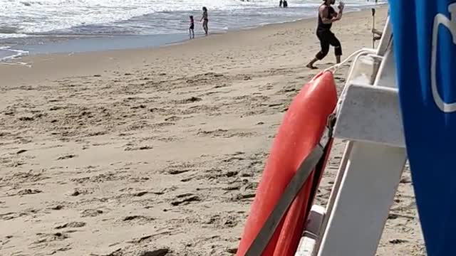 Guy in black punching air at beach
