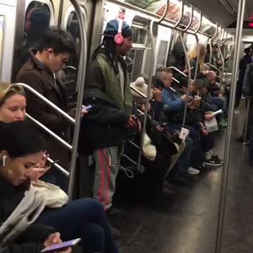 White headphones raps along to music on subway