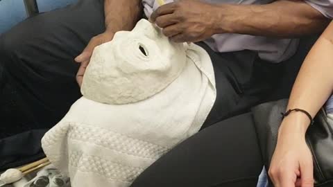 Man on subway train carving a white mask