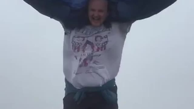 Person Struggles To Keep Their Jacket In Place Due To Strong Wind