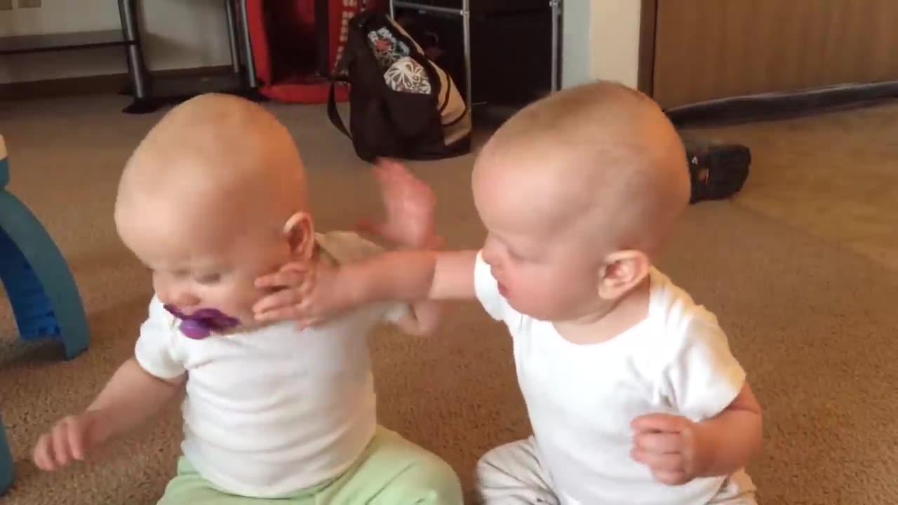 "Adorable Twin Baby Girls Engage in Playful Pacifier Tug-of-War 🍼👶"