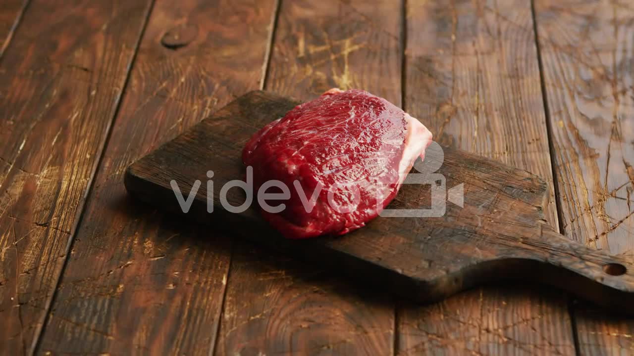 Big fresh piece of meat laid on wooden cutting board-From above view of fresh uncooked meat placed o