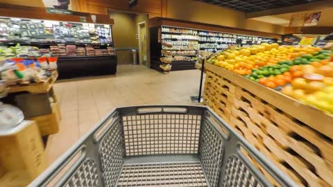 shopping cart rolling through the produce section of a grocery store