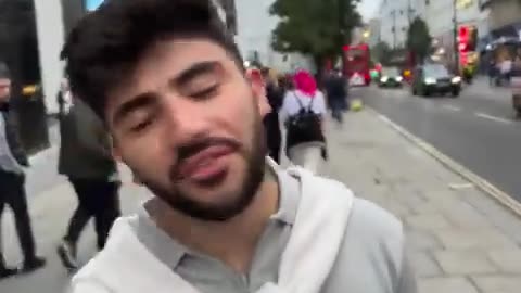 A Middle Eastern looking couple are seen talking down posters of Israeli captured children in London