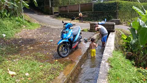 Clean motorcycle in water irigation with my children