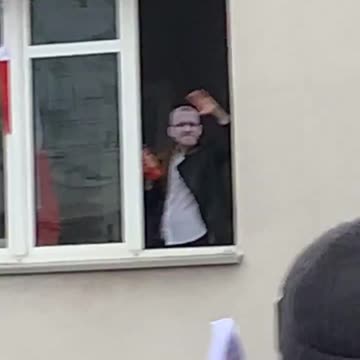 Grzegorz Braun waving from a window to participants of Poland's Independence March