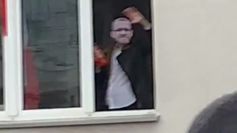 Grzegorz Braun waving from a window to participants of Poland's Independence March