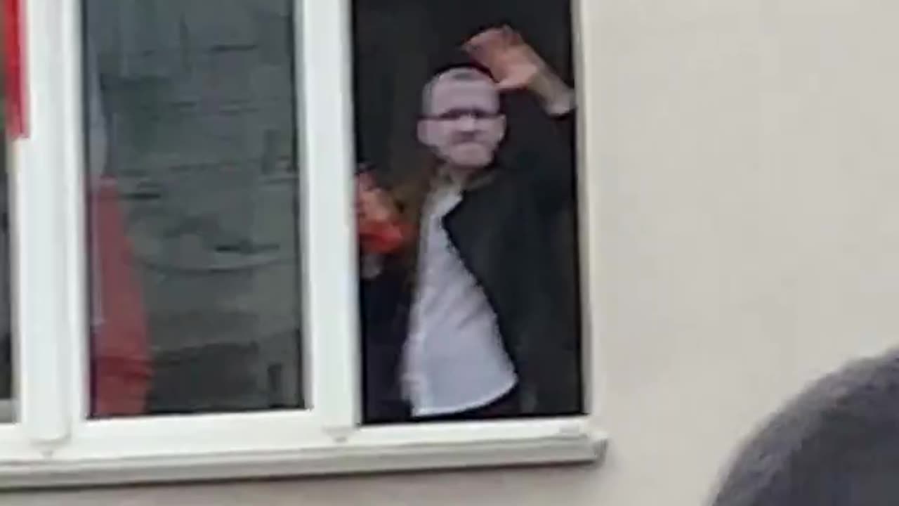 Grzegorz Braun waving from a window to participants of Poland's Independence March