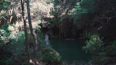 a Woman Walking Towards a Lagoon in the Forest