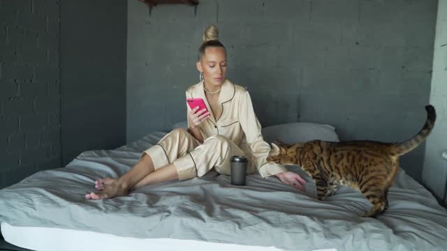 Woman in bed plays with cat