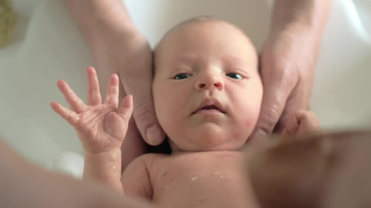 Parents bathing a newborn baby