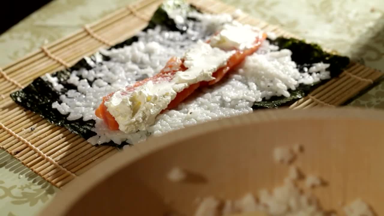 rolling a sushi roll filled with salmon