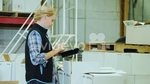 A Woman With A Tablet Holds Inventory In A Warehouse