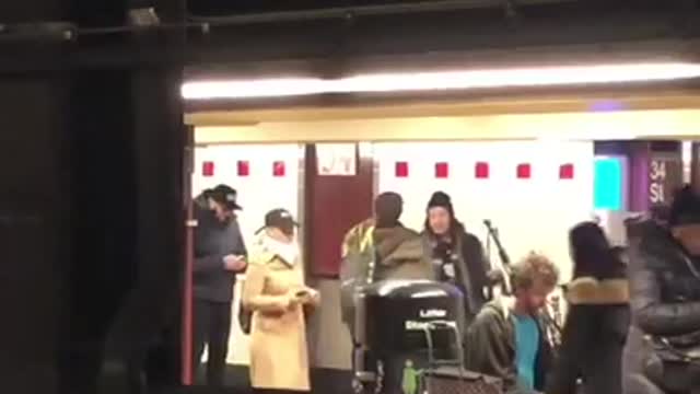 Man blue shirt playing bag pipes subway station