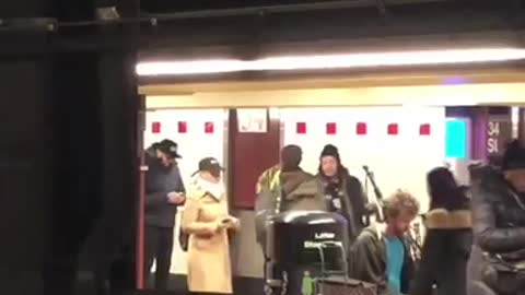 Man blue shirt playing bag pipes subway station