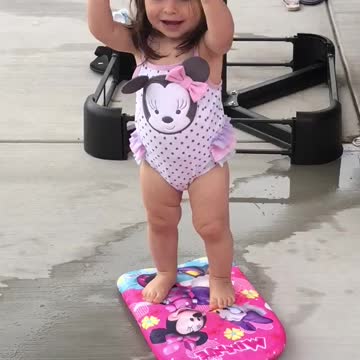 Small girl pink bathing suit stands on boogie board