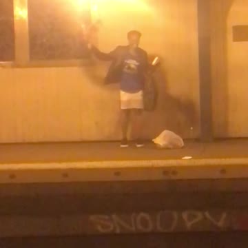 Woman in blue dancing and talking on subway platform