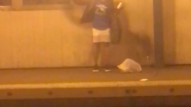 Woman in blue dancing and talking on subway platform