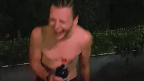 Guy in underwear jumps over bush night time