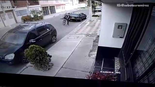 Surveillance camera man falls forward off bike between cars