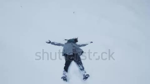 Girl falling in deep snow and making a snow angel.