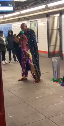 Man in sequin pants and sparkly red vest dances and sings in subway station