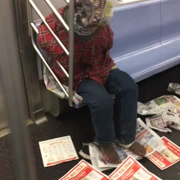 Red shirt guy surrounds self with newspapers and sleeps on subways