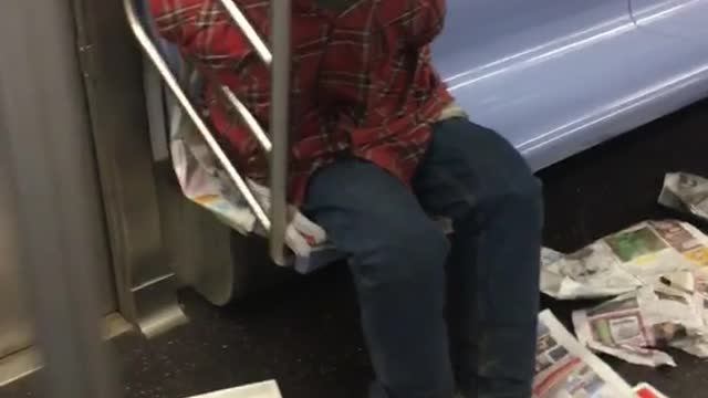 Red shirt guy surrounds self with newspapers and sleeps on subways