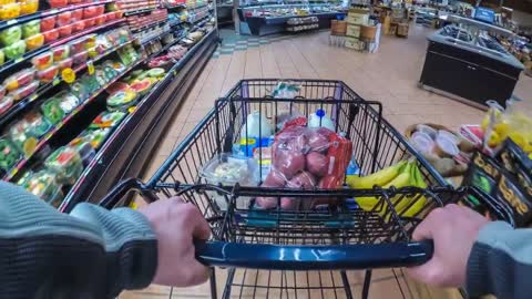 adult male pushing a metal shopping cart through the produce section of a supermark free stock video