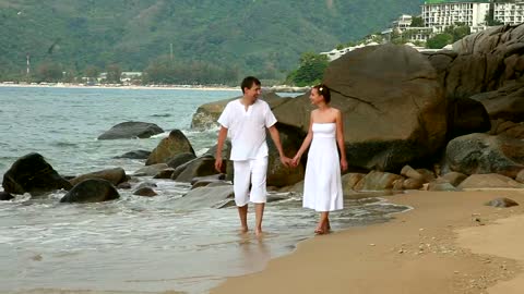 Couple holding hands walking in the beach